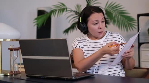 Junge Frau trägt Headset, Telefonkonferenz auf Laptop, spricht mit Online-Lehrerin, die arbeitet