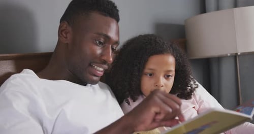 Father Reading Picture Book to Young Child in Bed