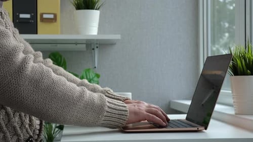 Man Freelancer Working on Laptop at Homeoffice Drinks Coffee or Tea From a Cup
