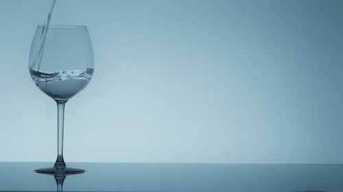 Studio-Shooting von Wasser, das in transparentes Glas fließt, auf weißem Hintergrund