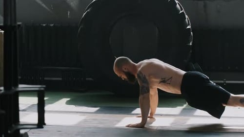 Young Caucasian Bearded Male Athlete Doing Pushups in Large Gym Hall Stopping to Rest Exhausted
