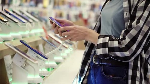 Waist Shot of Unrecognizable Woman's Hands Chooses a Smartphone in an Electronics Store