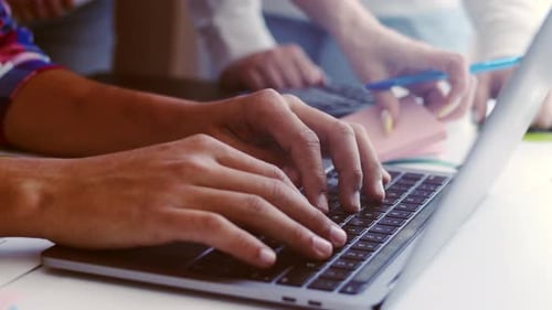 Hands of office workers typing on laptop keyboard and the hands of a woman with a calculator