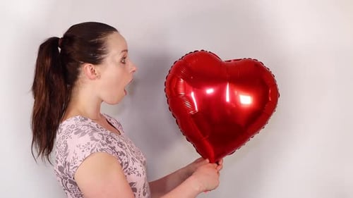 Woman Smiles with Red Heart-Shaped Balloon