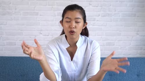 Young Woman Talking, Sitting on Couch Indoors