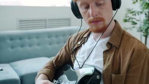 Man Playing Electric Guitar Wearing Headphones Indoors