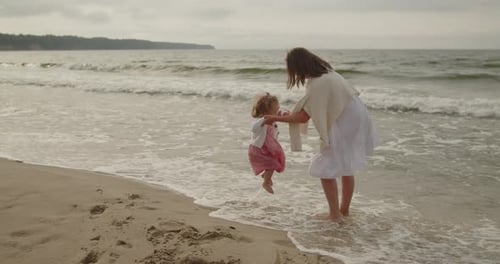 Mother and Daughter Have Fun Playing in the Sea Water on the Beach Together