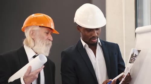 Architect and Engineer Looking at Scketch Blueprint at Office and Discussing Project