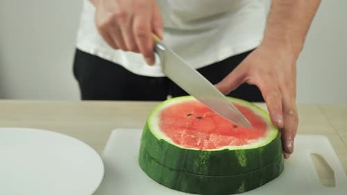 Halved Watermelon Being Cut into Quarters on Board