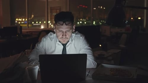 Man Working Late on Laptop, Eating Pizza