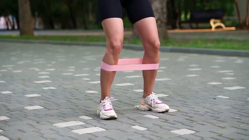 Woman Doing Squats with Resistance Band Outdoors