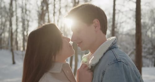 Un beau jeune couple heureux s'amuse ensemble dans une forêt d'hiver ensoleillée