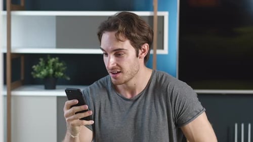 Surprised Man Reacts to Phone News Indoors