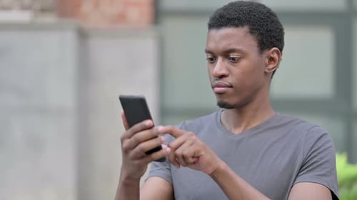 Young Adult Using Smartphone Outdoors in Urban Setting