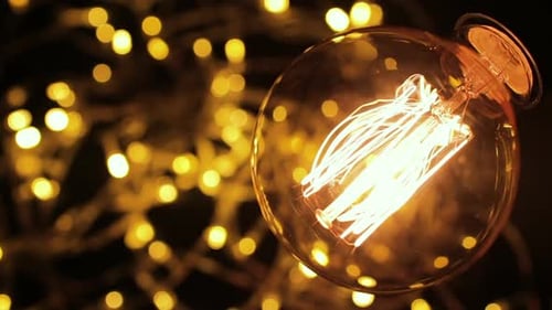 Flashing Old Vintage Light Bulb Glowing Against Background of Lights