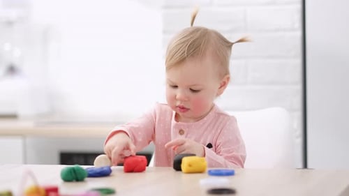 Adorable Infant Plays with Colorful Modeling Clay at Table