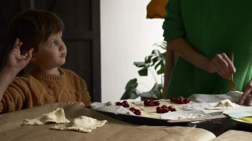 Child Watching Adult Baking Cherry Pastries at Home