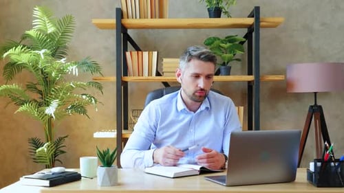 Businessman in home office conducts remote online video conference call with company employees