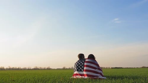 Friends Wrapped in American Flag on Sunny Day