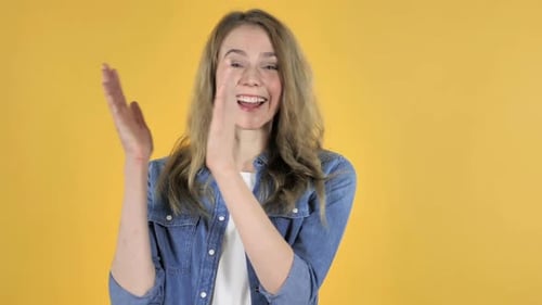 Enthusiastic Woman Clapping Hands Against Yellow Background