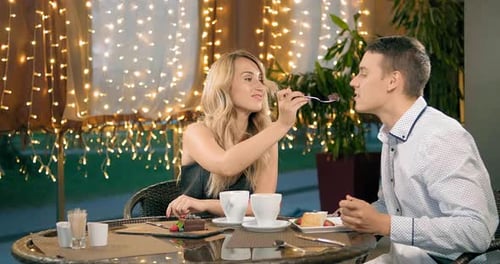 Couple Eating Cake at Restaurant Table at Night