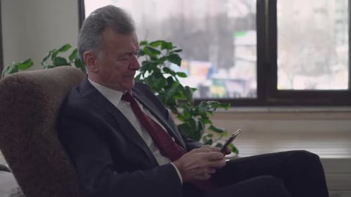 Man In Suit Uses Smartphone While Relaxing