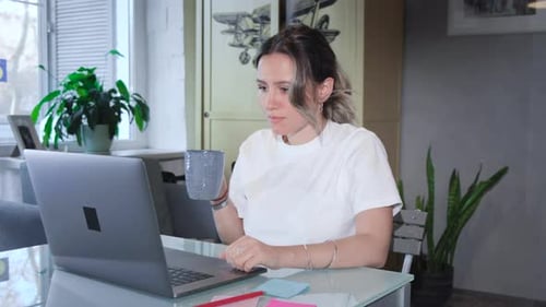 Attractive young woman enjoying what she is doing as she works at computer in her beautiful