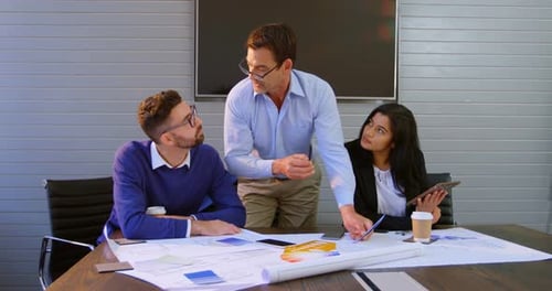 Colleagues Collaborate Over Technical Drawings in Office