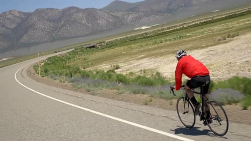 A man road biking on a scenic road.