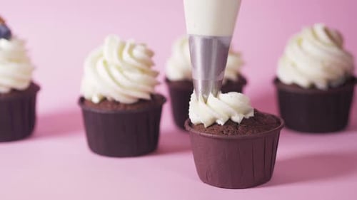 Creamy Frosting Being Piped Onto Chocolate Cupcake