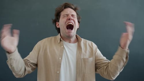 Zeitlupenporträt eines gestressten jungen Mannes, der schreit und mit den Armen schlägt und dann in