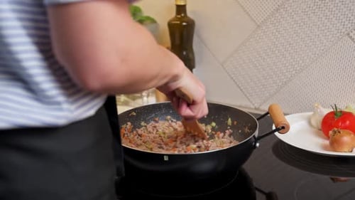 Person Cooking Meat and Vegetables in a Pan