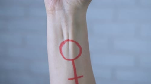 Woman Clenched Fist with Gender Symbol Drawn on Arm