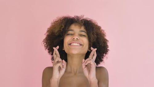 Mujer joven alegre levanta las manos con los dedos cruzados