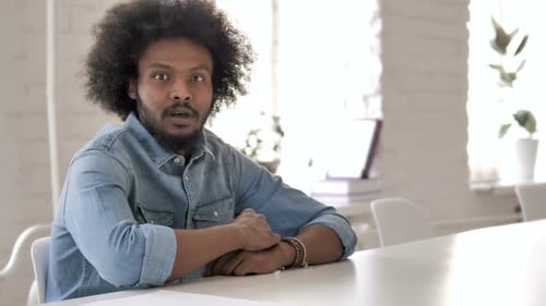Man with Curly Hair Looks Shocked in Office