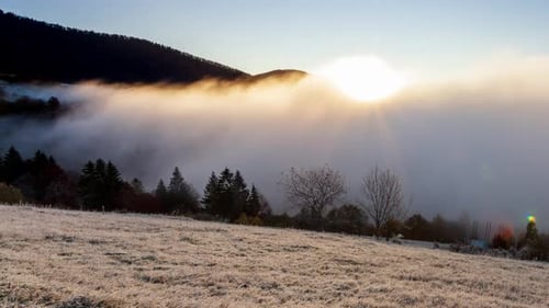 Sun Rises From Behind Mountain Top Fog Moves and Rises Up at Dawn on Summer Morning in Mountains