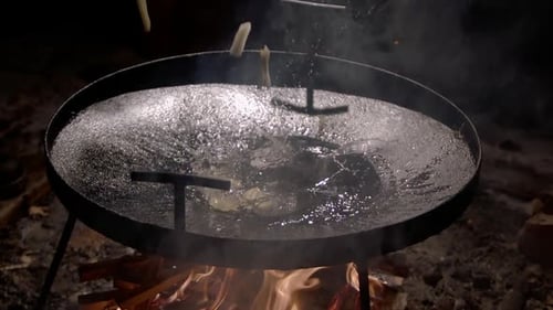 Food Frying in a Large Pan Over Fire