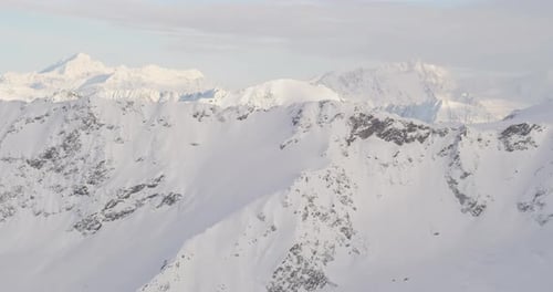 Aerial helicopter shot closeup on rippling glacier, Alaskan mountains in background, drone footage