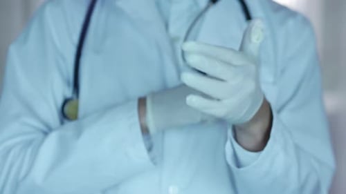 Medical Professional Puts on White Protective Gloves