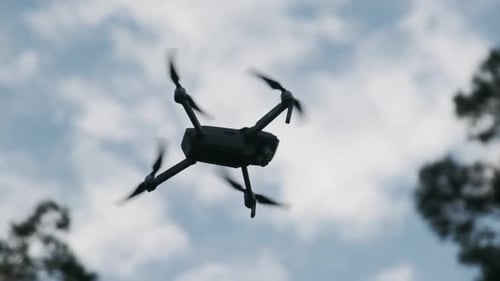 Drohne hängt in der Luft vor dem blauen Himmel, Ansicht von unten. Zeitlupe 240 Fps