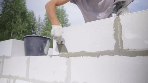 Worker Applies Cement to Blocks on New Wall