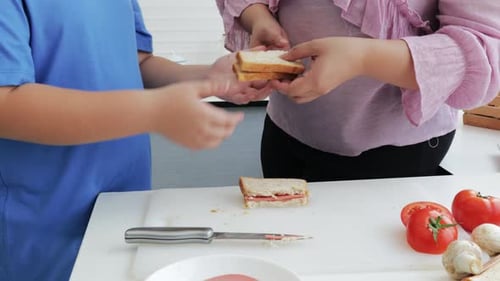 Close-up of Plus size Mom and son eating vegetable salad and sandwich together.