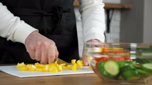 Close up hands chef man in apron sliced fresh yellow pepper on board in kitchen