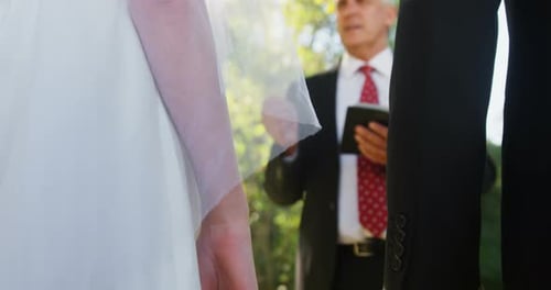 Wedding Couple Holding Hands during Outdoor Ceremony