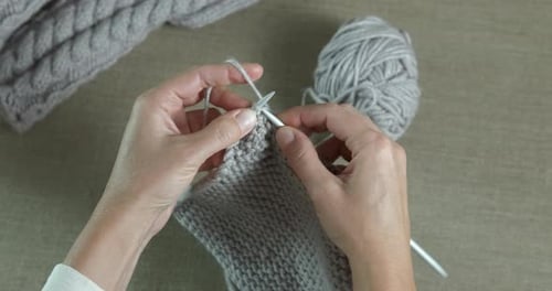 Hands Knitting with Grey Wool and Needles