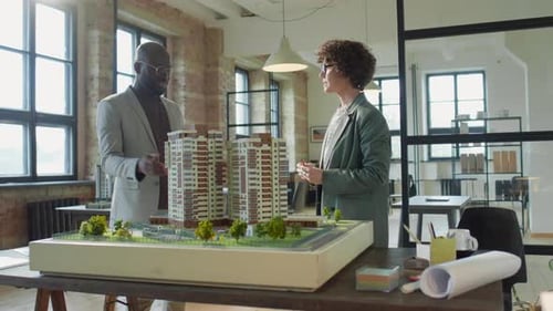 Two Architects Discussing Building Project in Office