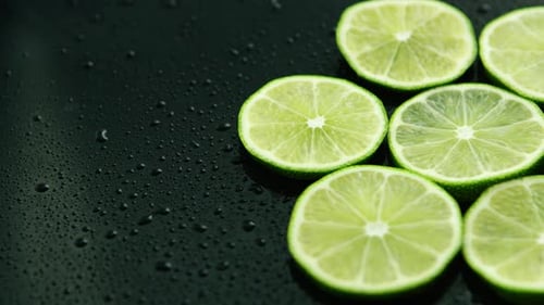 Fresh Lime Slices on Wet Black Background