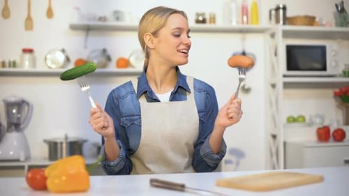 Pretty Girl Choosing Cucumber Instead Sausage, Low-Calorie Food vs Carbohydrates