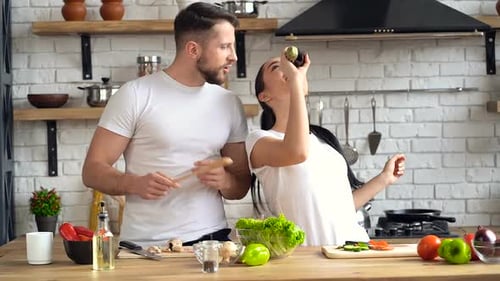 Couple Cooking, Singing, and Dancing in Kitchen