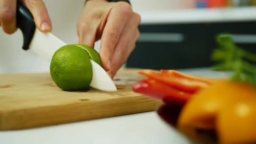 Cutting Lime on Wooden Board with Knife